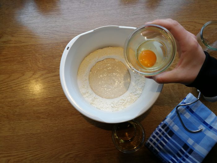 Ei wird in Schüssel mit Mehl gegeben