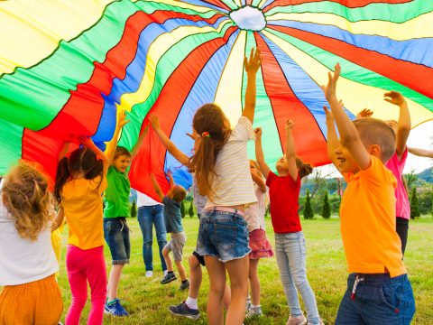 Kinder spielen unter Fallschirm