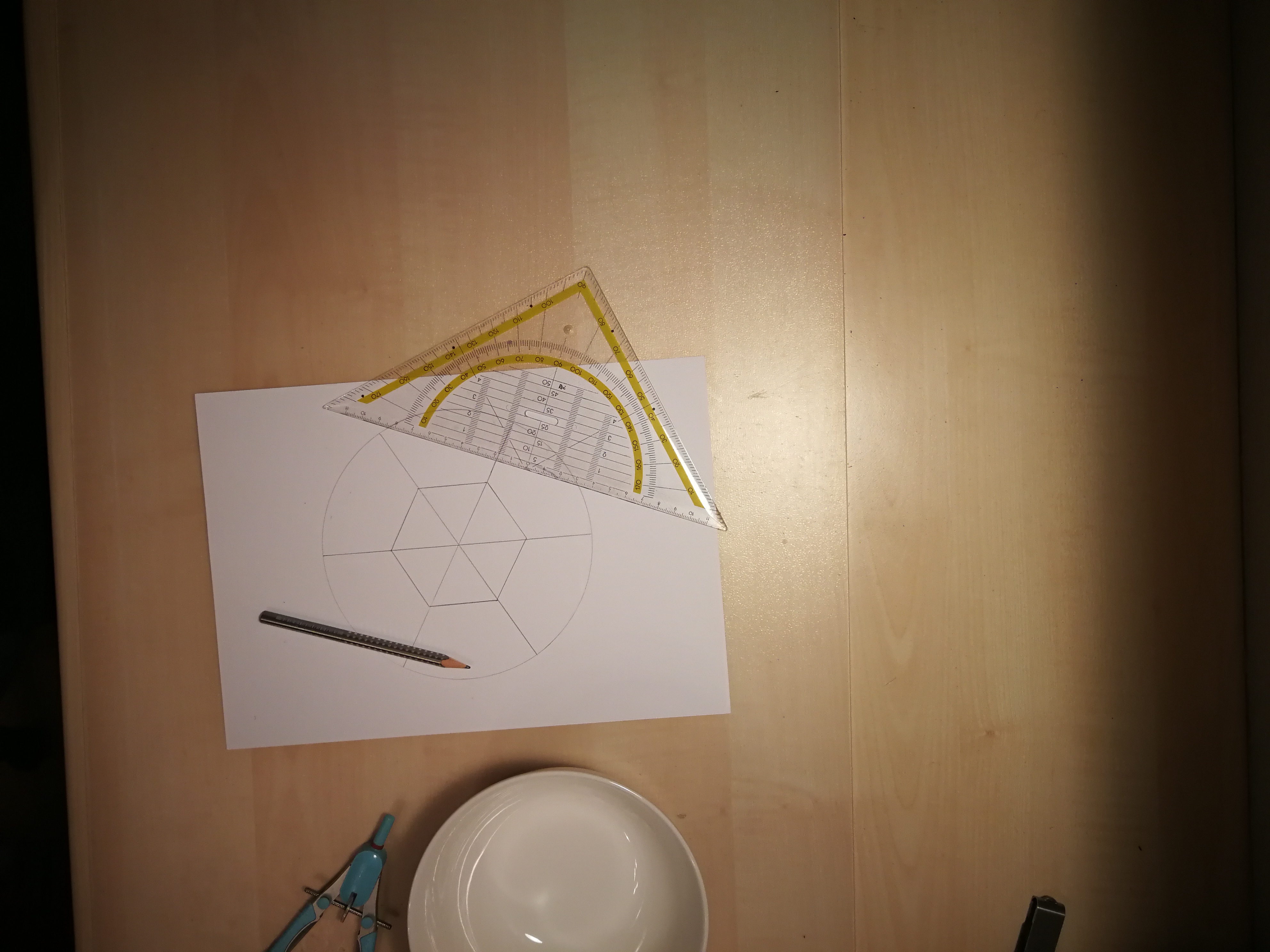 Geodreieck, Bleistift, Papier mit aufgezeichnetem Kreis und darin ein Sechseck